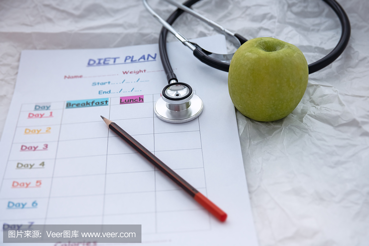 聽診器和青蘋果旁邊放著模糊的飲食時(shí)間表計(jì)劃,背景上,燈光周圍模糊,保健理念